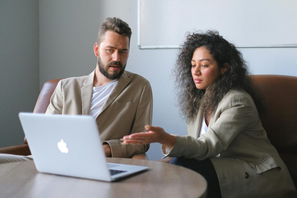 two people talking in front of a laptop